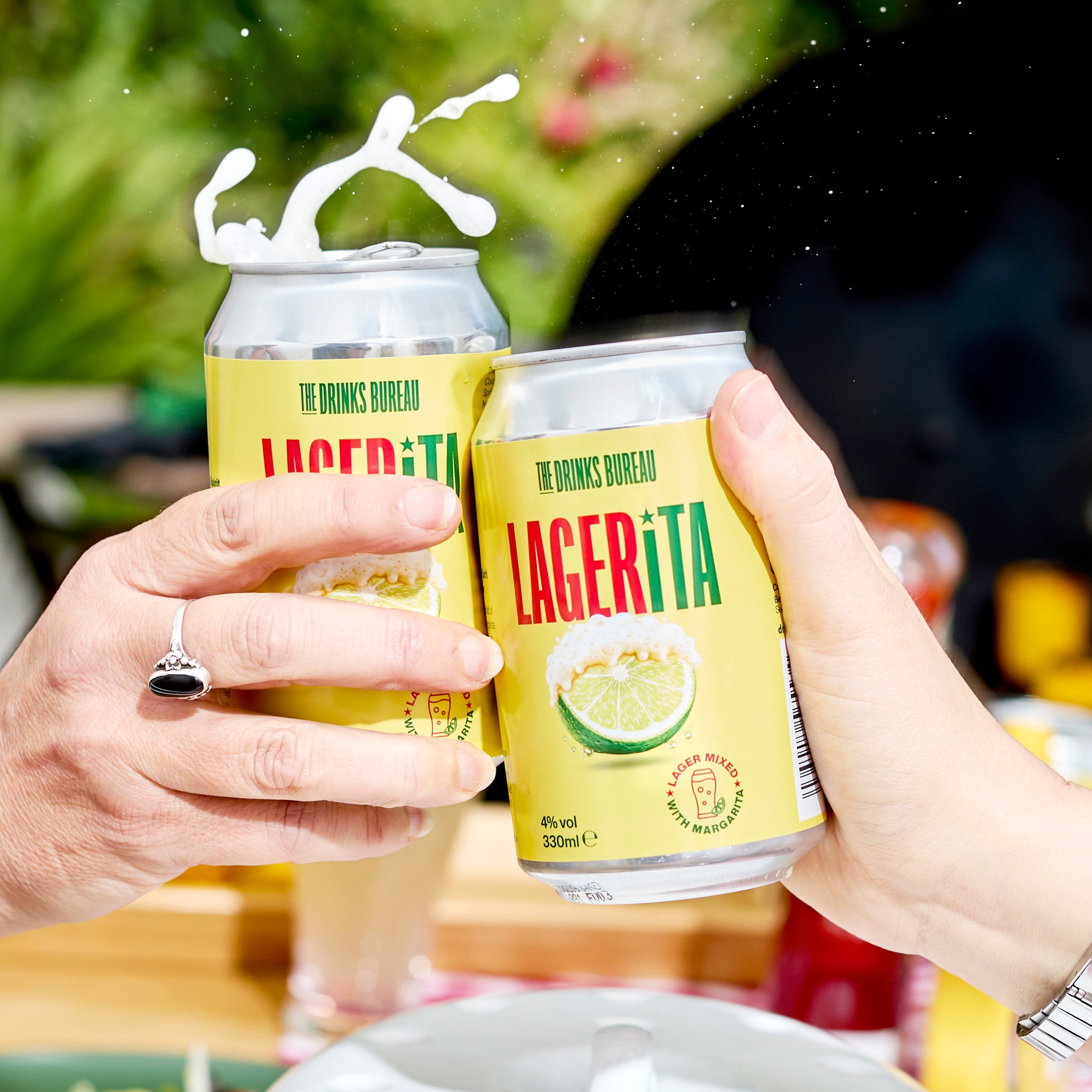 Two cans of LACERITA beer being held by hands with a blurred outdoor background.